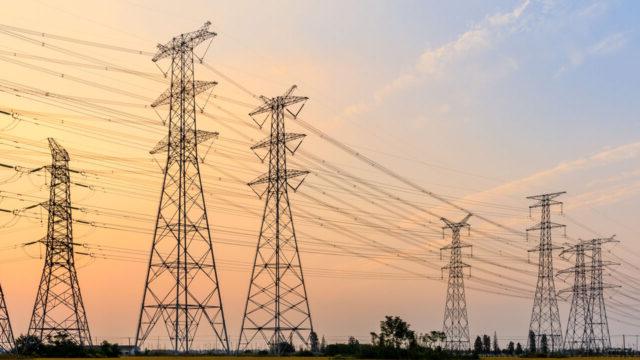 High-voltage power transmission lines in front of a sunset